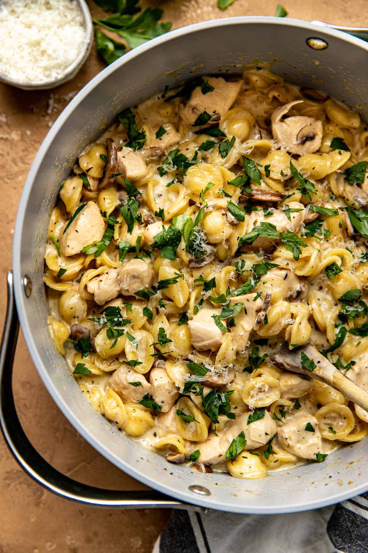 marsala pasta in a large pot garnished with parsley and cheese.
