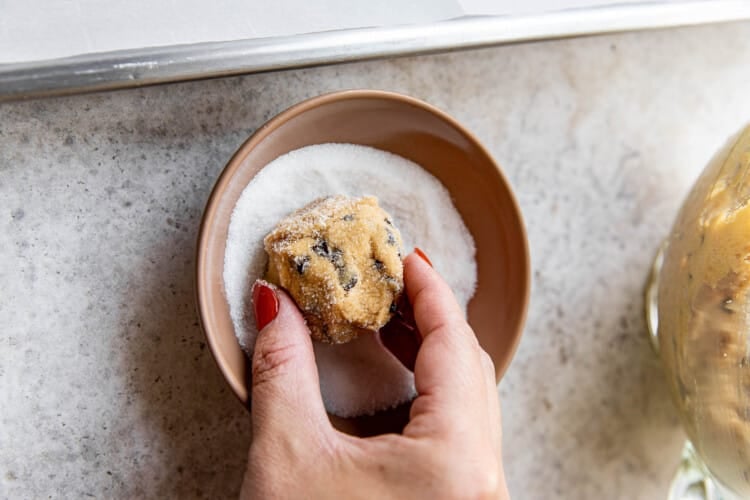 woman's hand dipping fluffernutter cookie dough ball in sugar