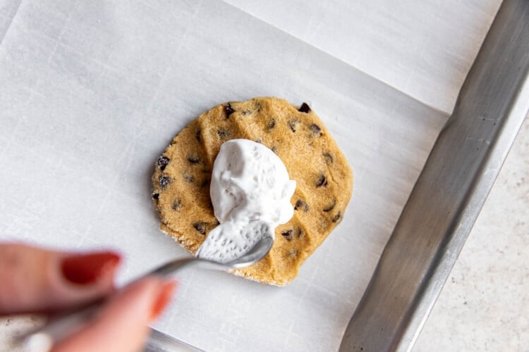 woman's hand adding marshmallow to flutternutter cookie dough on a baking sheet