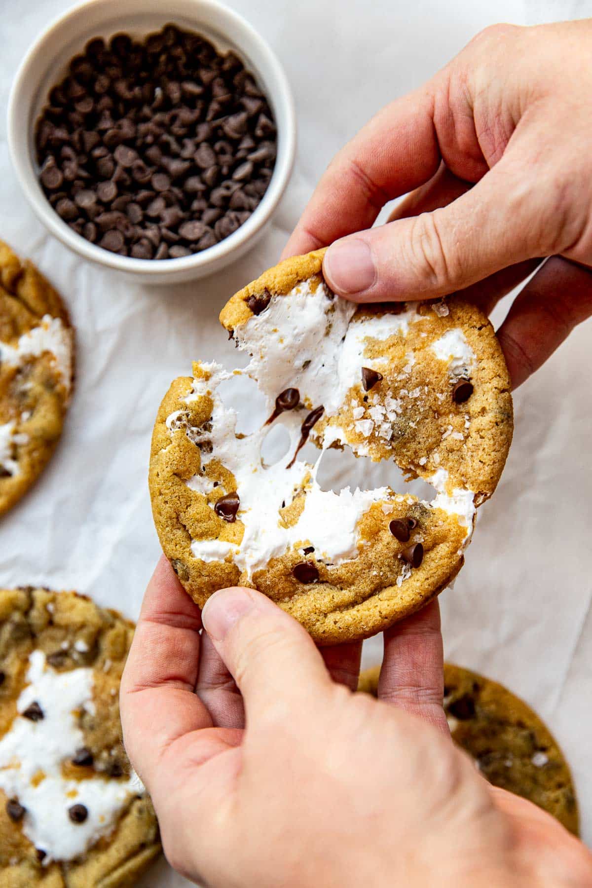 hands pulling apart a cookie with marshmallow fluff in the center. 