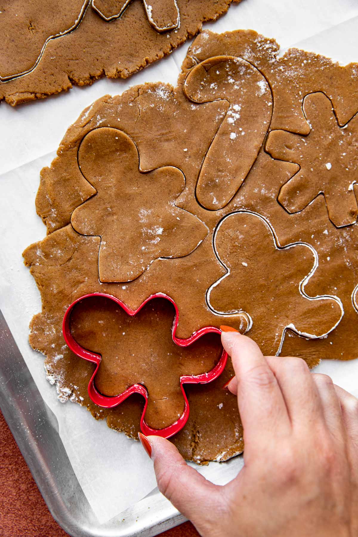 gingerbread dough being cut into shapes with cookie cutters. 