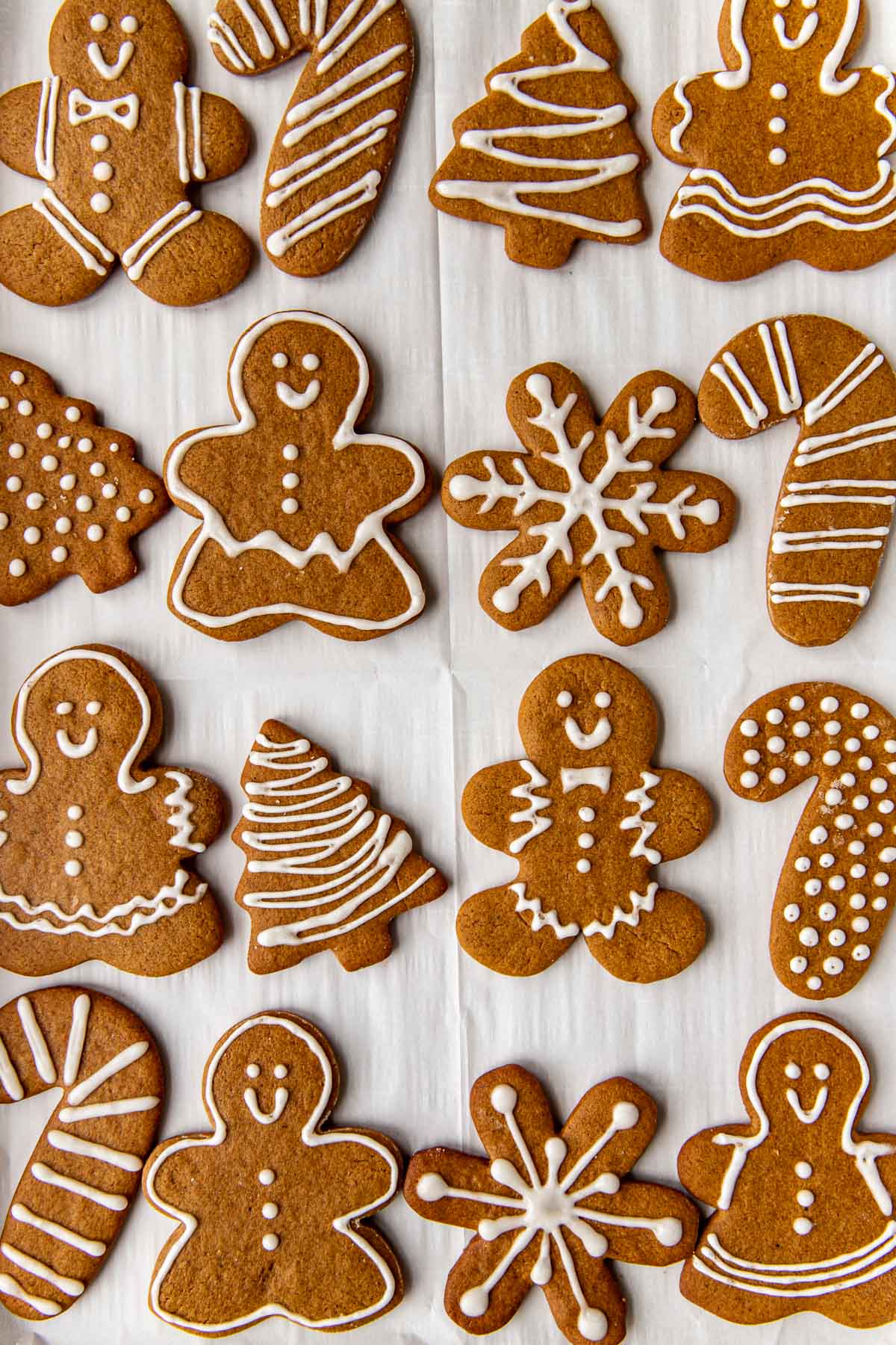 gingerbread man cookies on a piece of white parchment paper decorated with icing. 