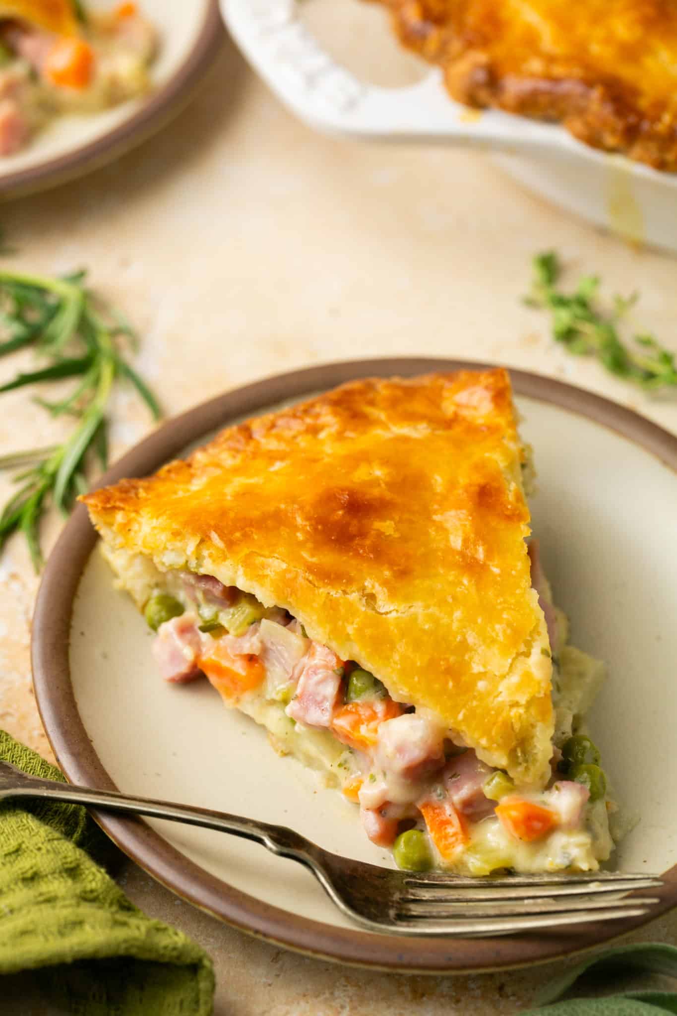 a slice of pot pie on a white plate with a fork. 