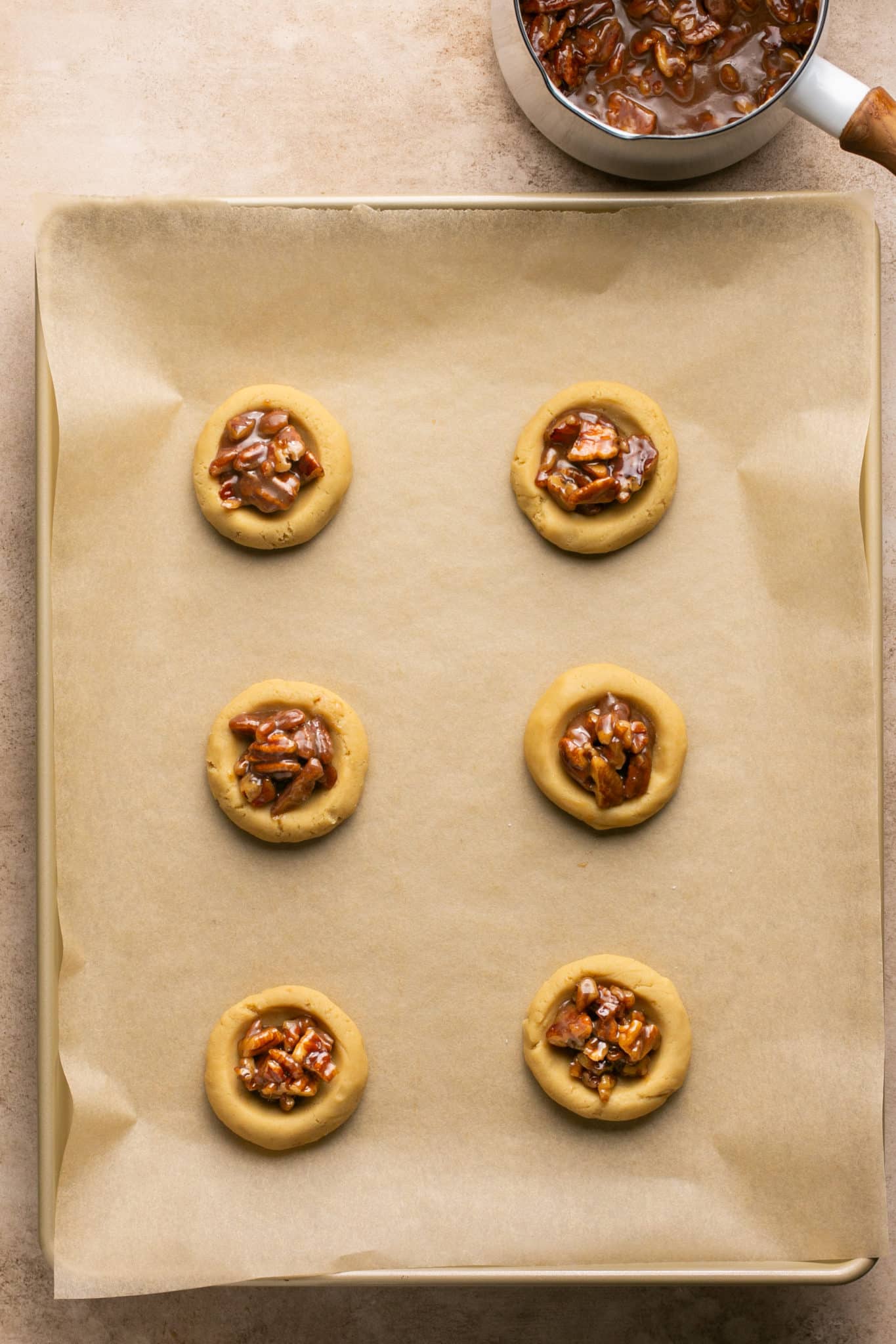 cookie dough on a baking sheet filled with pecan pie filling in the center. 