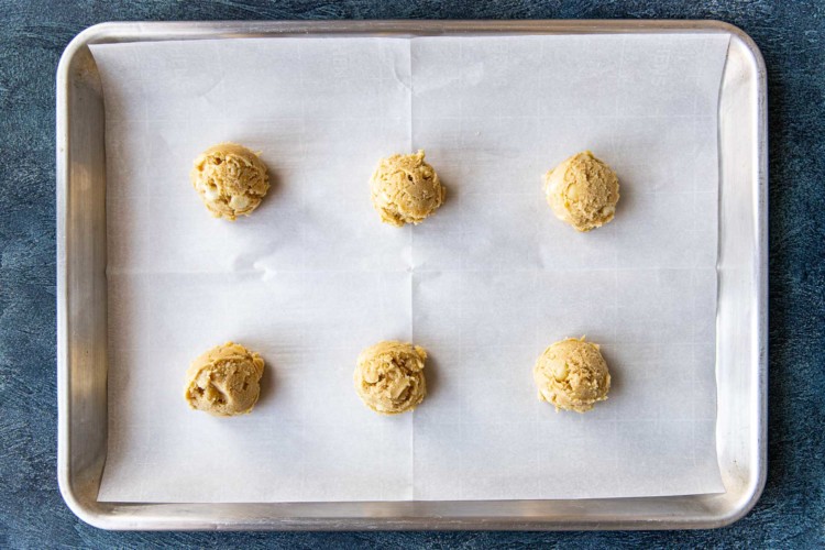 six balls of cookie dough on a baking sheet