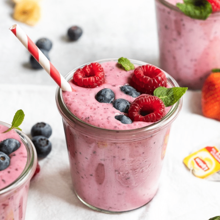 pink smoothie topped with berries and a red and white straw