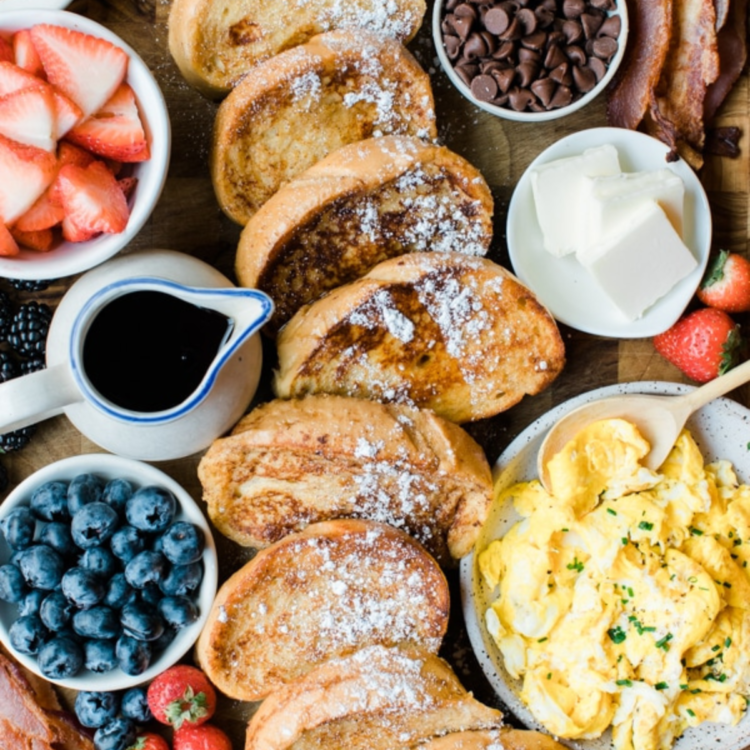 board with french toast slices, berries, eggs, and toppings