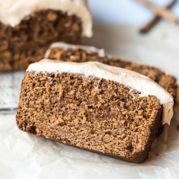 slice of gingerbread loaf with white icing on a piece of parchment paper