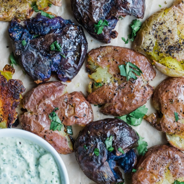 multi-colored baby potatoes smashed with herbs atop and cream sauce on the side