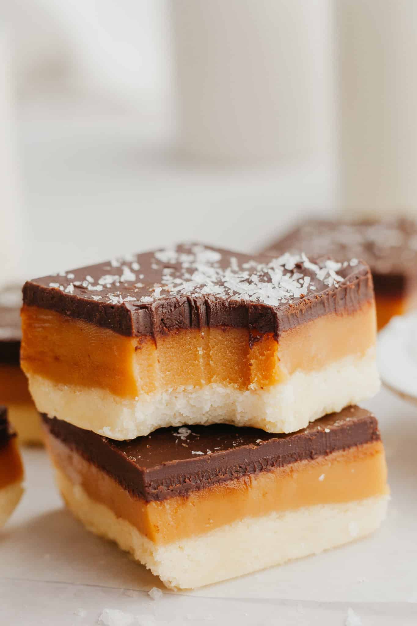 a bite taken out of a millionaire shortbread bar topped with flaky sea salt. 