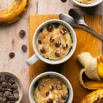 banana mug cake in a white ceramic mug topped with peanut butter and chocolate chips.