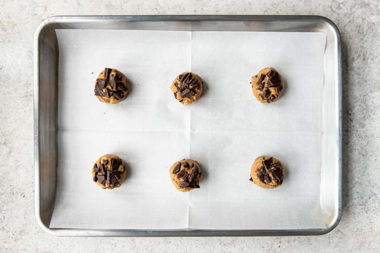 cookie dough on parchment paper with chocolate chunks on top.