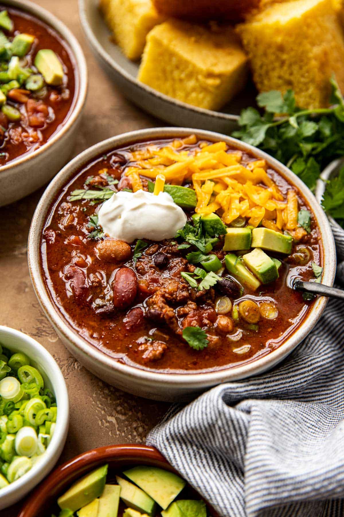 chili in a bowl with avocado, cilantro, and sour cream on top. 
