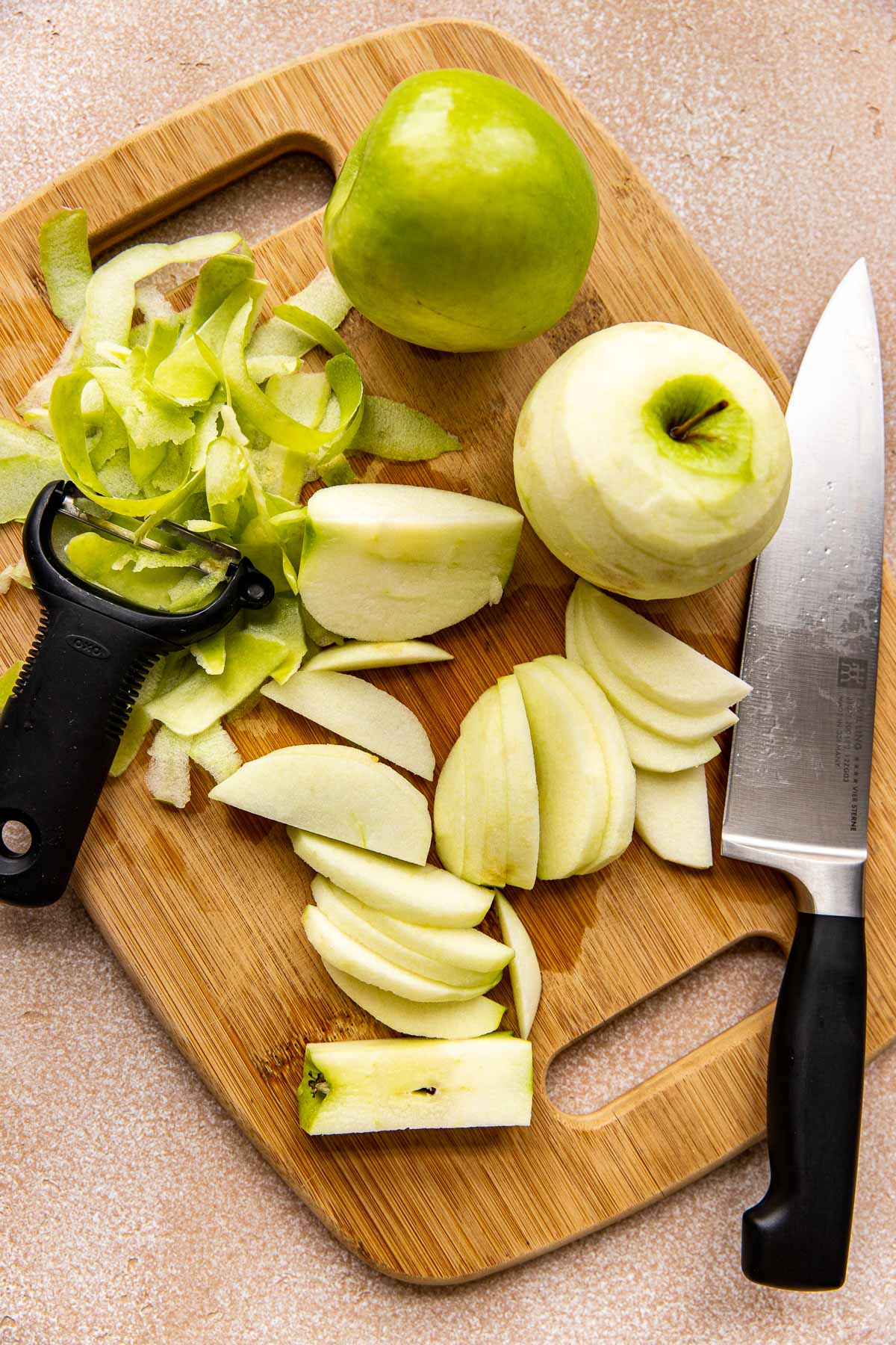 granny smith apples peeled and sliced on a cutting board. 