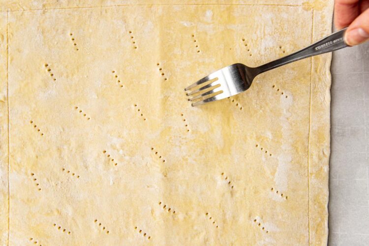a fork pricking holes into puff pastry dough.
