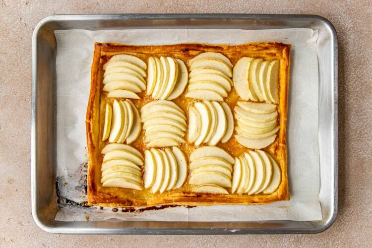an apple tart on a sheet pan lined with parchment.