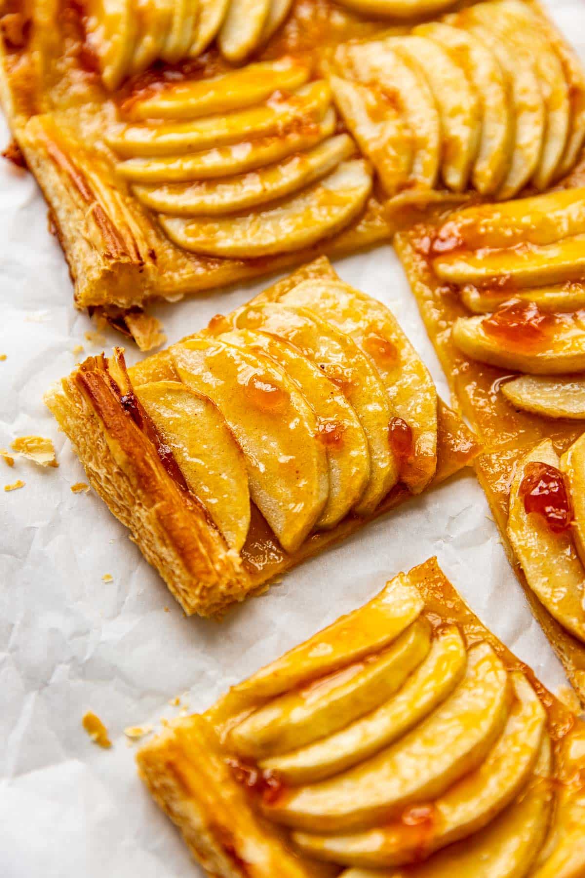 an up close image of an apple tart made with puff pastry and apricot preserves brushed on top. 