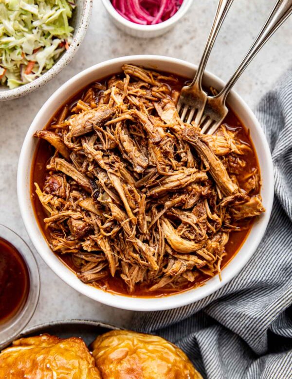 pulled pork in a white bowl with two forks.