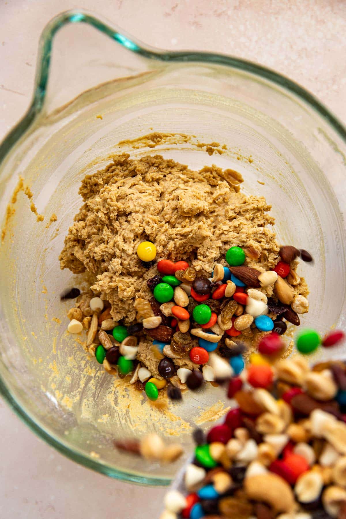 trail mix being poured into cookie dough.