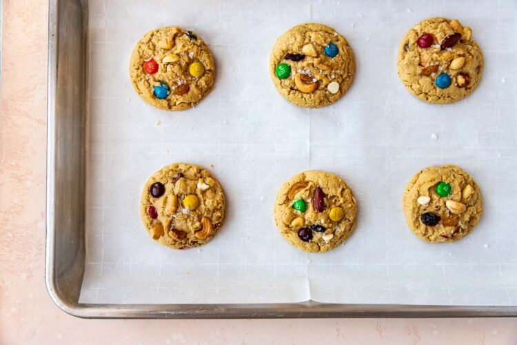 freshly baked trail mix cookies on a baking sheet lined with parchment paper.