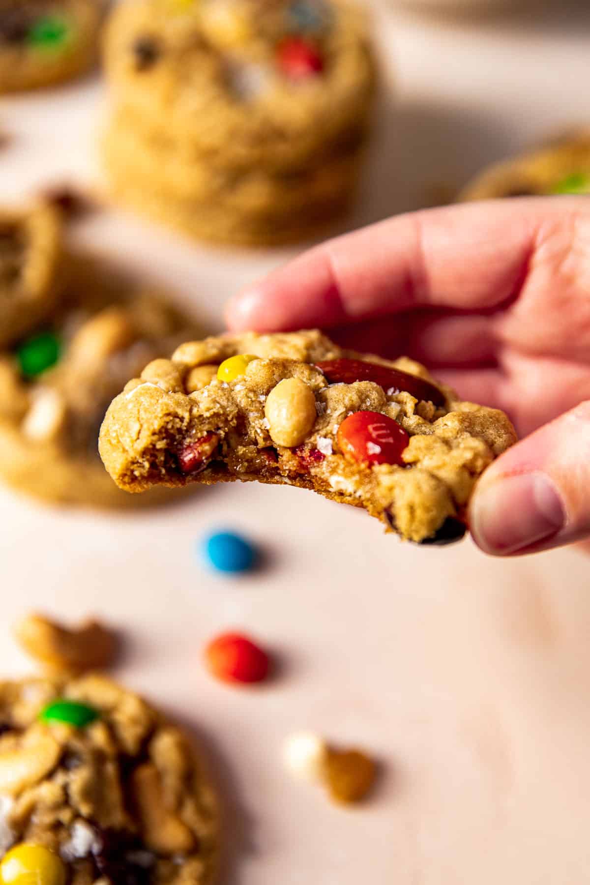 a hand holding a cookie with a bite taken out of it. 