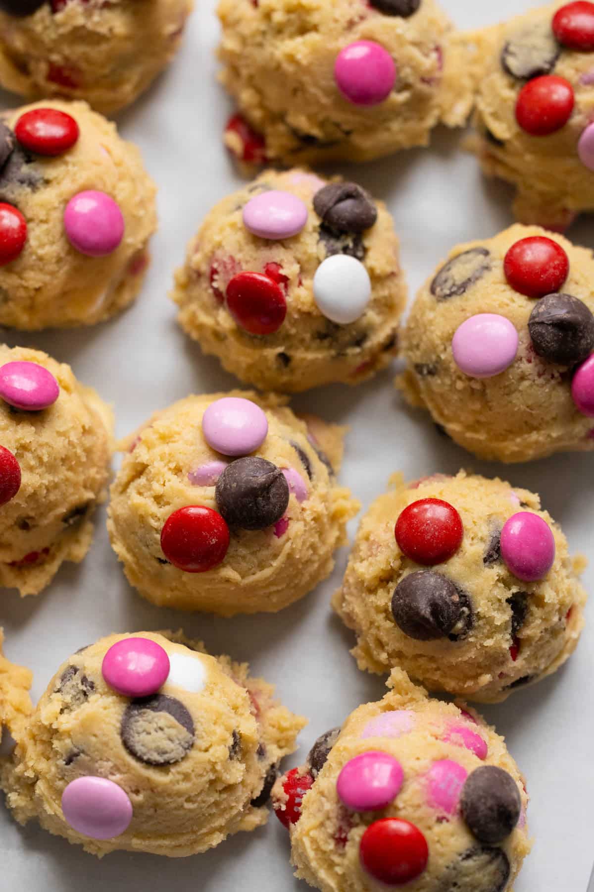 cookie dough on parchment paper garnished with m&ms and chocolate chips on top. 