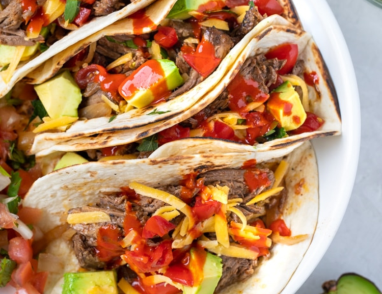 tacos with beef, avocado, and sauce in a white bowl