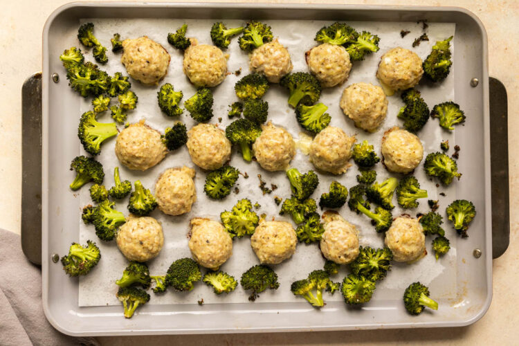 baked chicken meatballs and roasted broccoli on a sheet pan.