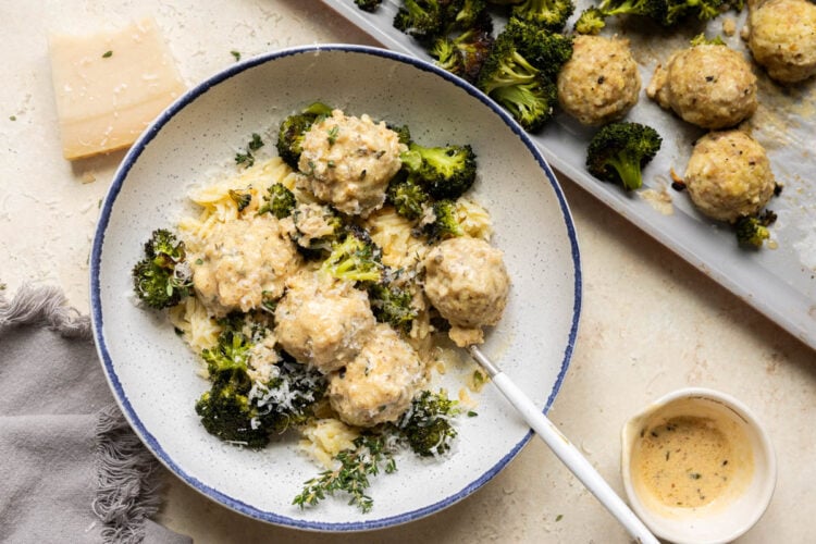 Chicken meatballs, broccoli and orzo in a bowl with sauce on top.