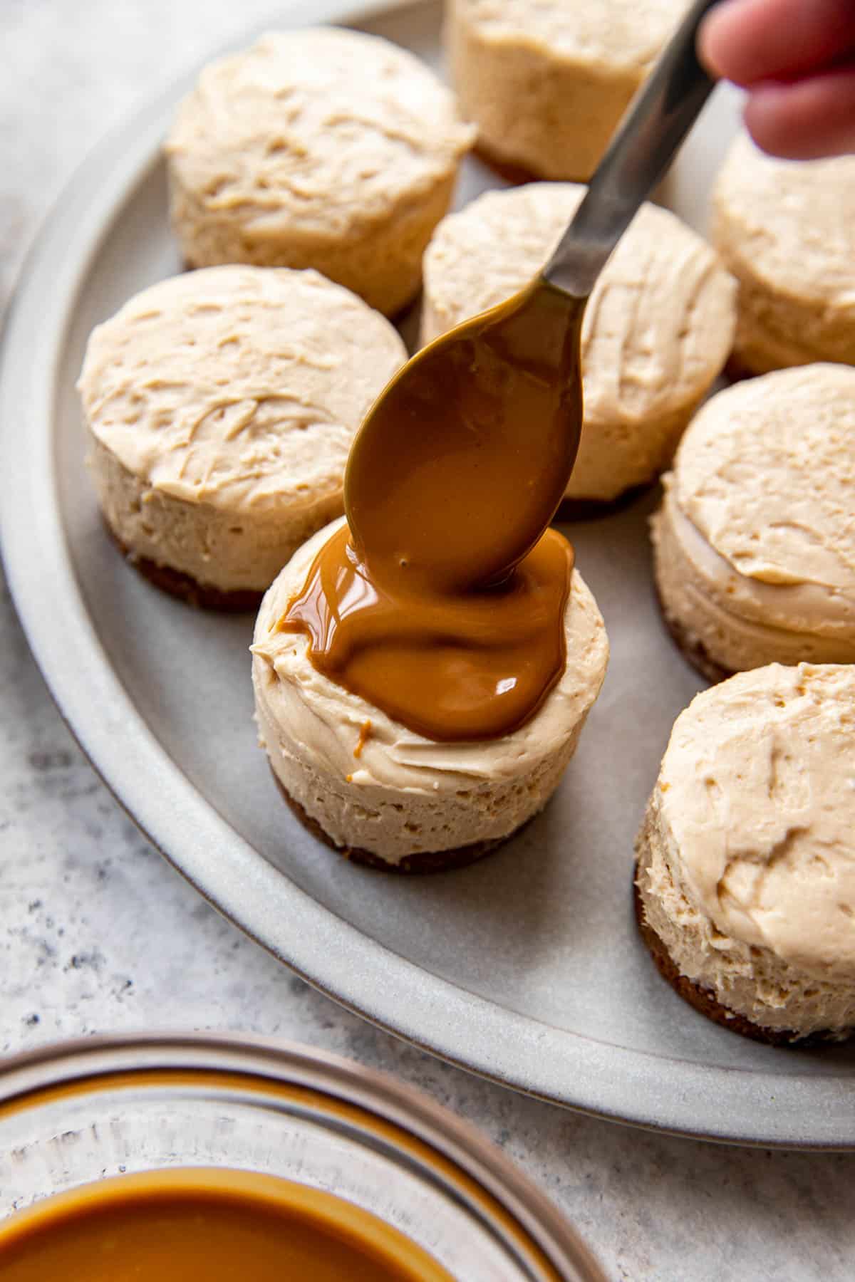 cookie butter being spooned onto cheesecake.