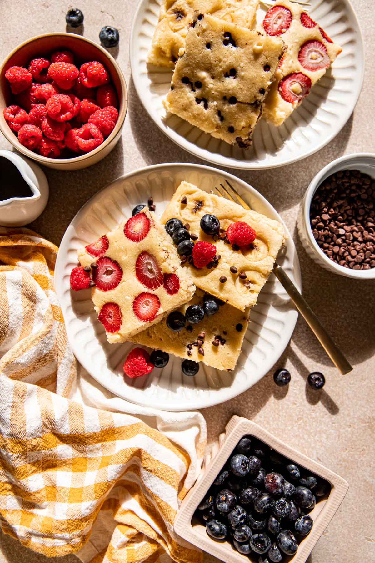 sheet pan pancakes on white plates with fresh berries. 