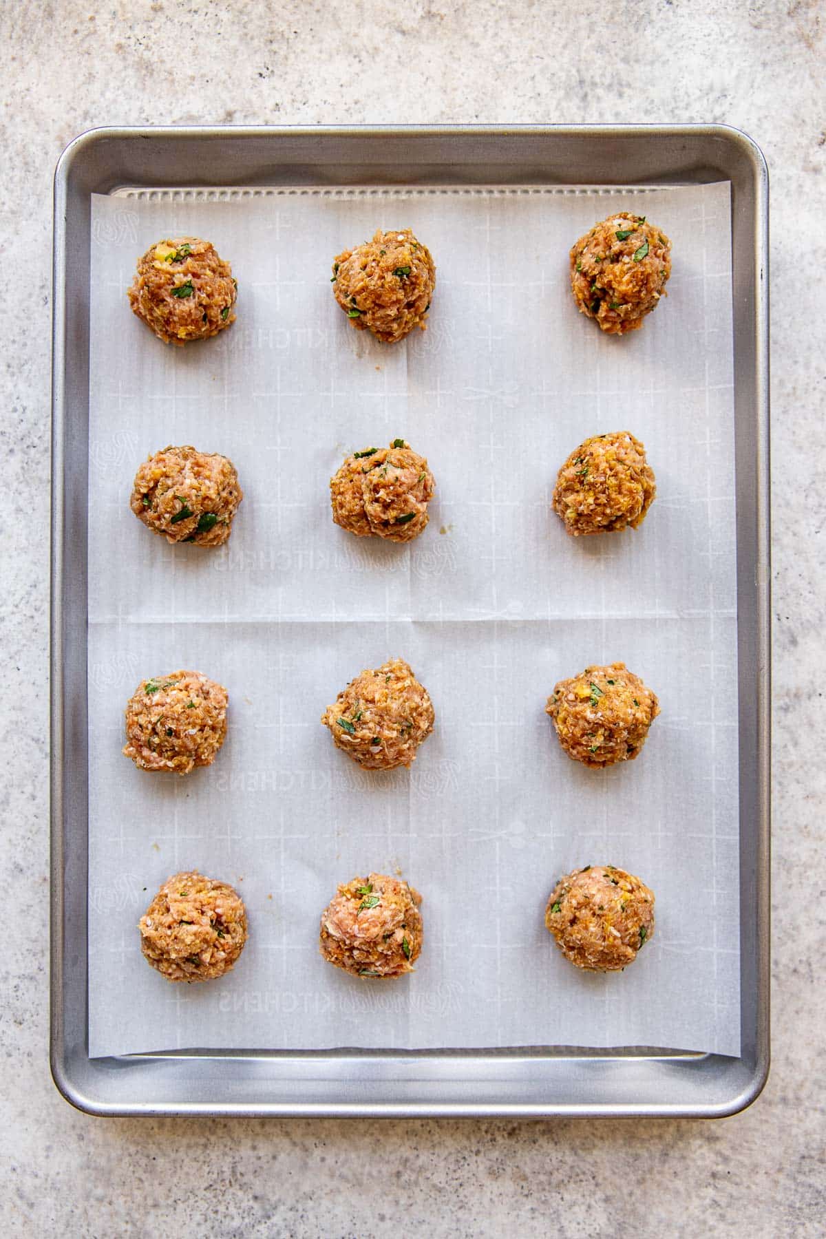 ground turkey meatballs on a parchment paper lined cookie sheet. 