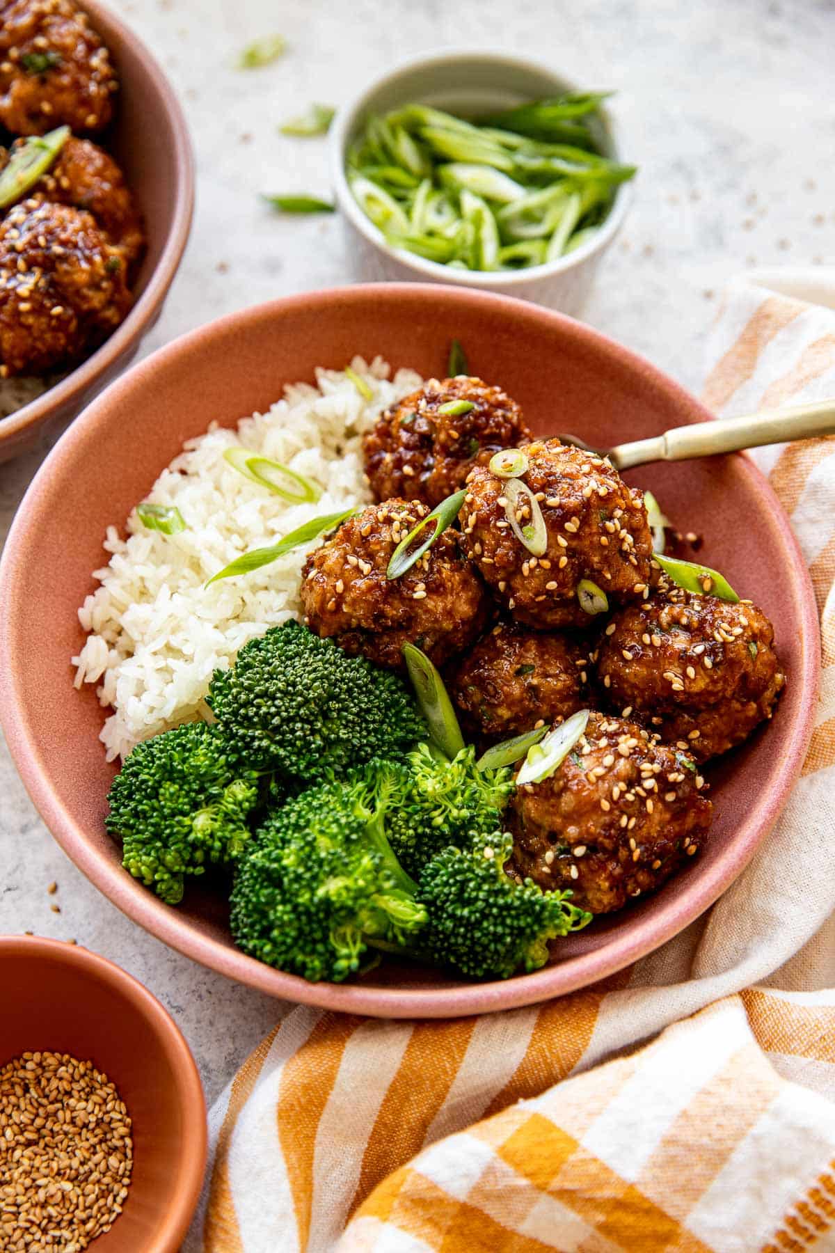 sriracha meatballs in a pink bowl with broccoli and white rice. 