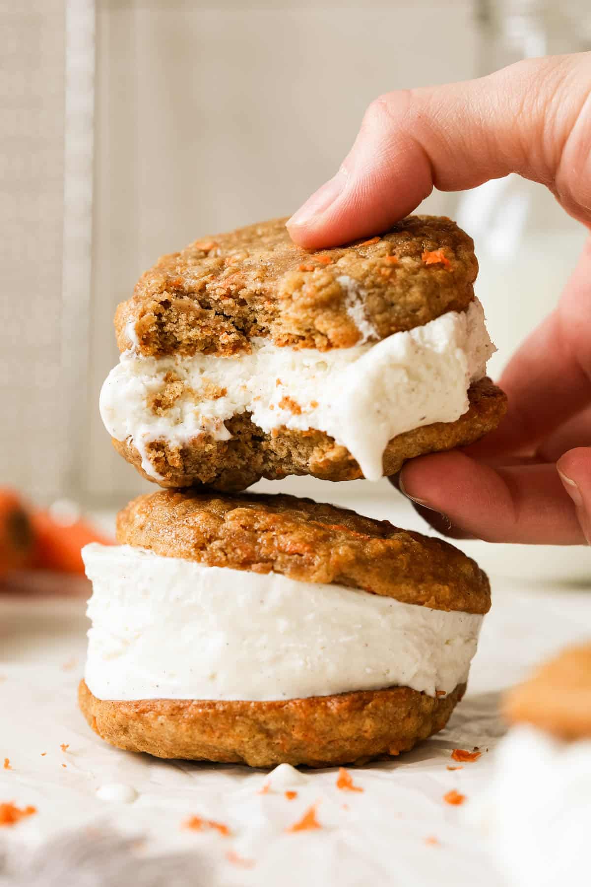 a hand holding an ice cream sandwich that has a bite taken from it. 