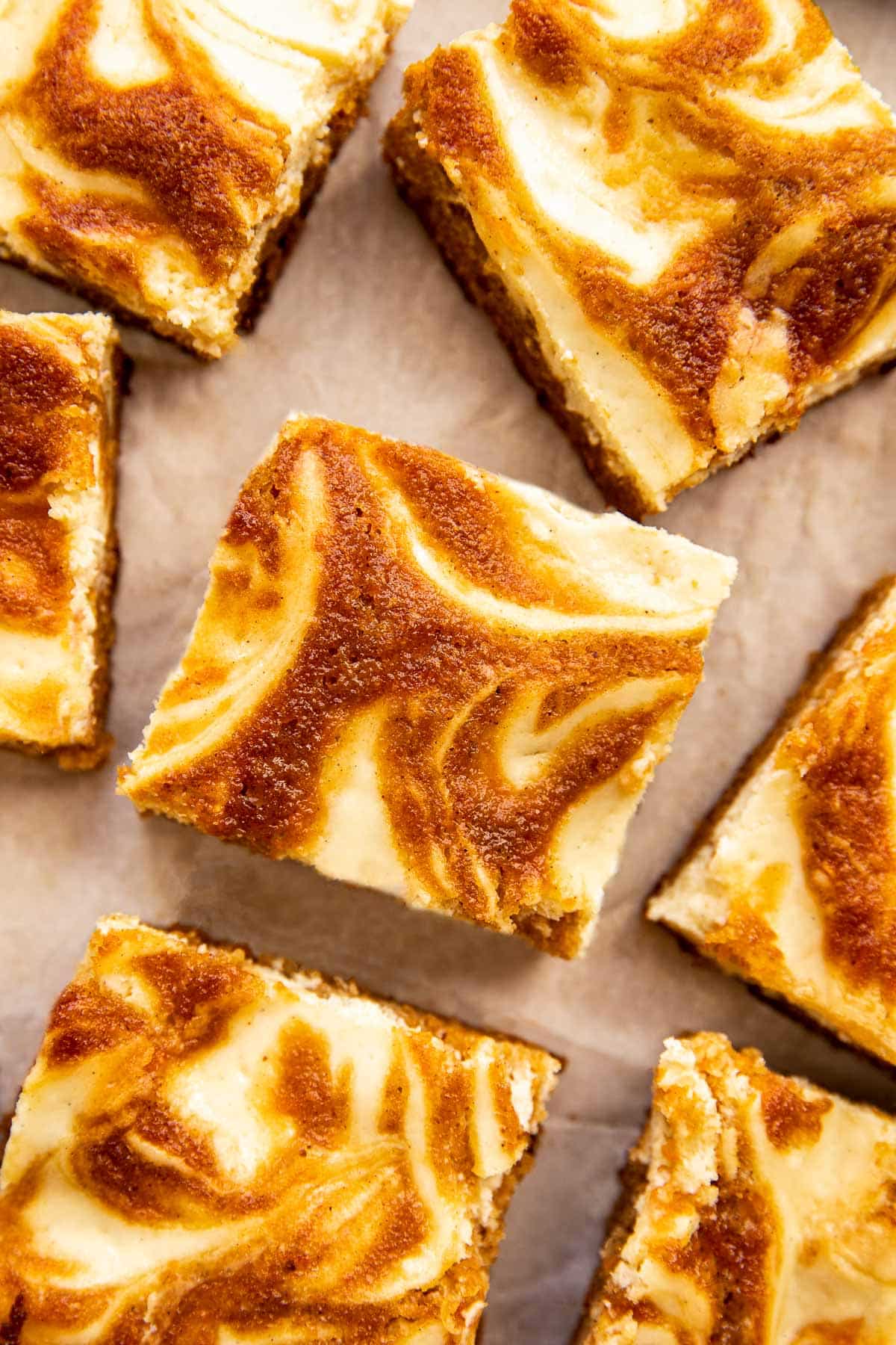 a carrot cake cheesecake bar cut into squares on parchment paper. 