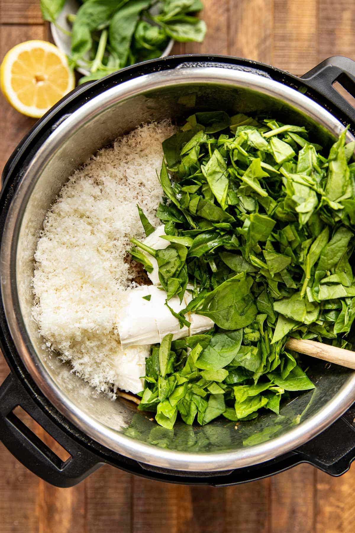 spinach, parmesan and cream cheese being stirred into instant pot. 