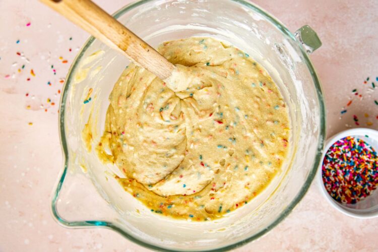 cake batter with rainbow sprinkles in a glass mixing bowl.