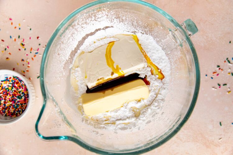 cream cheese, butter, and vanilla bean paste in a glass mixing bowl.