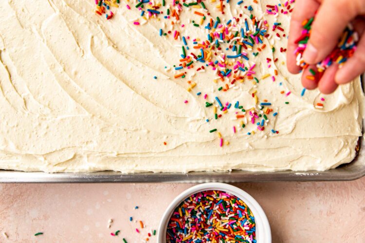 rainbow sprinkles being garnished on top of frosting.