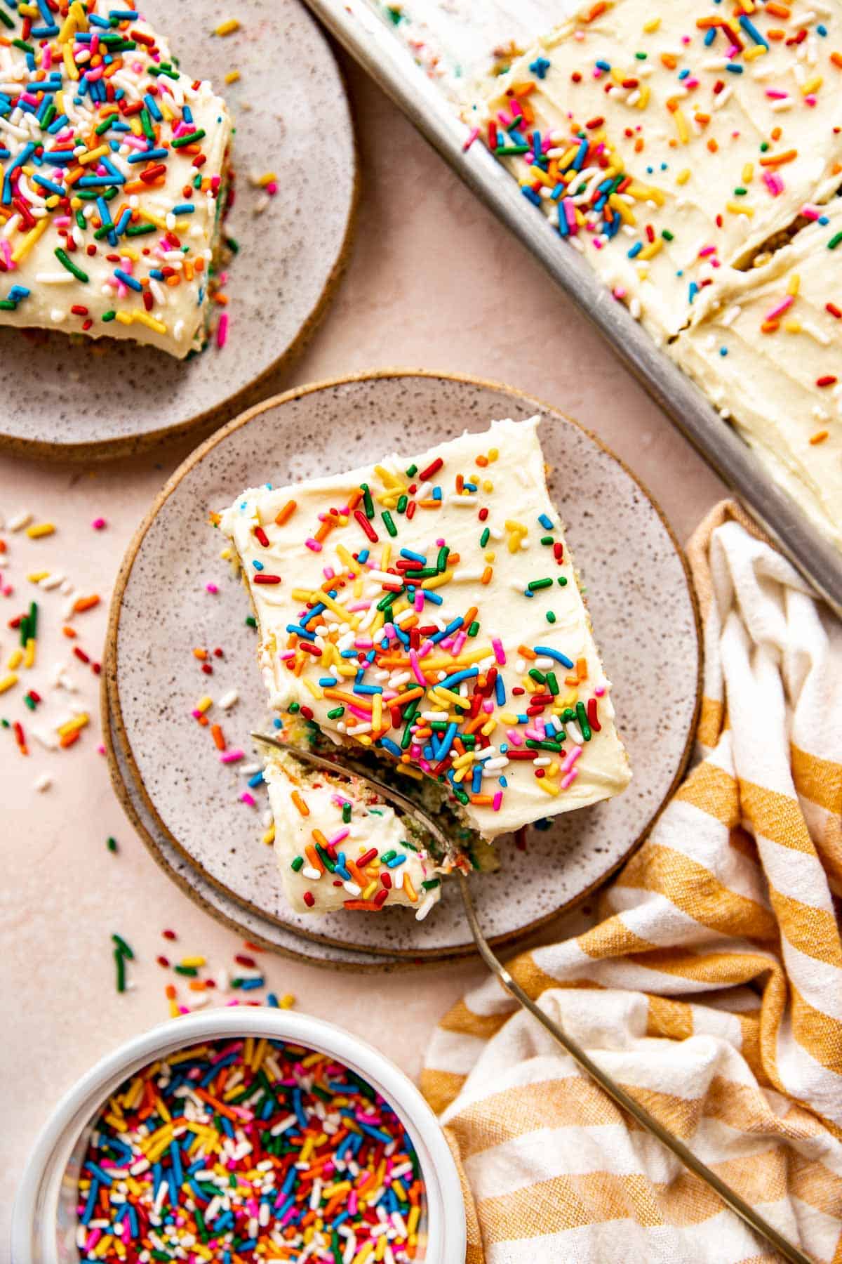 a fork taking a bite out of a piece of funfetti cake. 