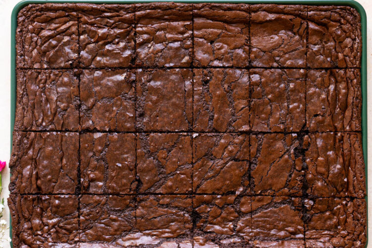 brownies cut into squares on a green sheet pan.