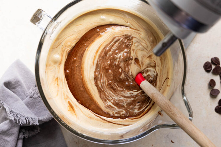 chocolate being stirred into egg and sugar mixer in a glass bowl.