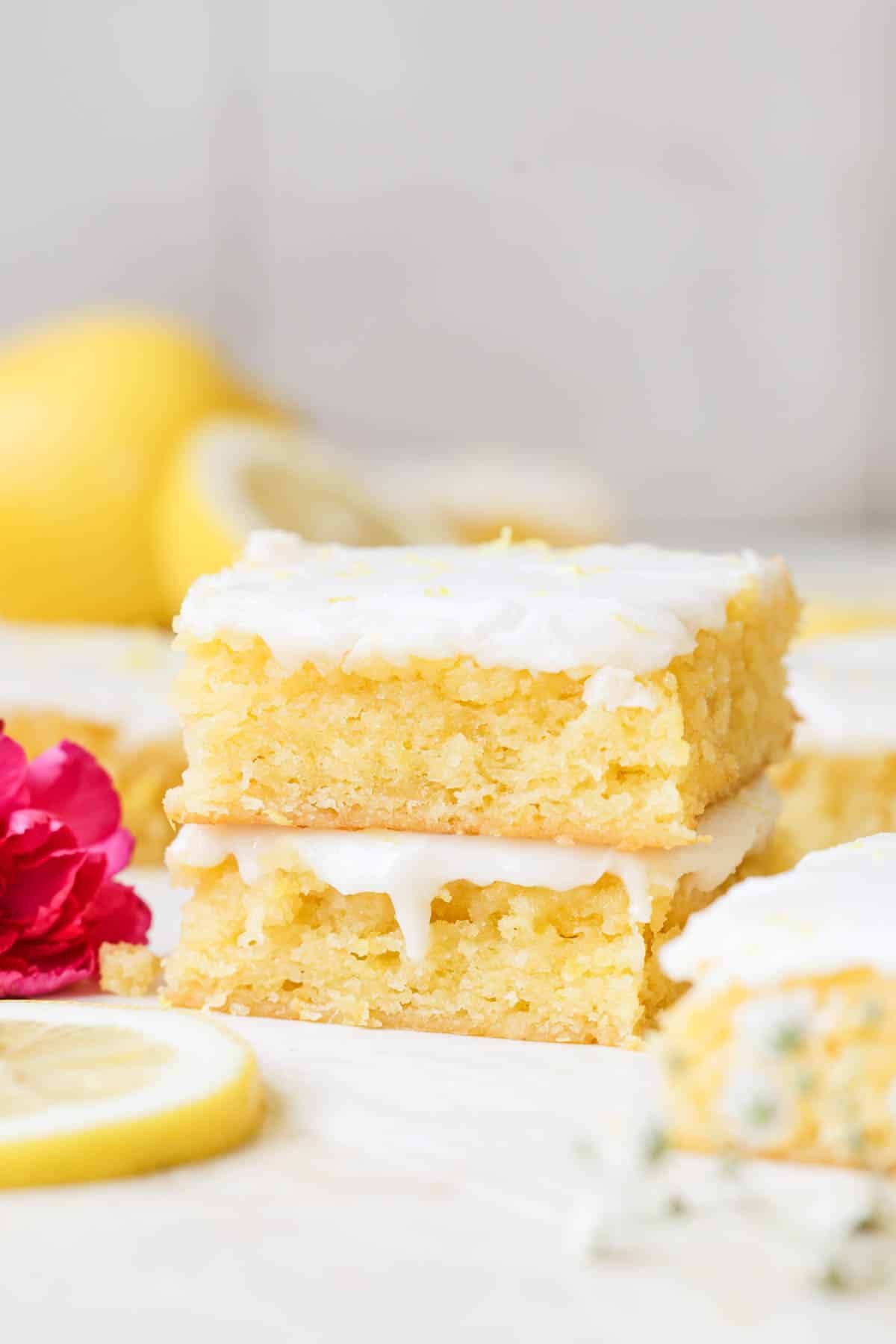 lemon brownies stacked on top of each other with a glaze on top. 