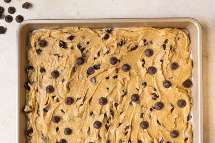 chocolate chip cookie dough on a baking sheet spread out into one even layer.