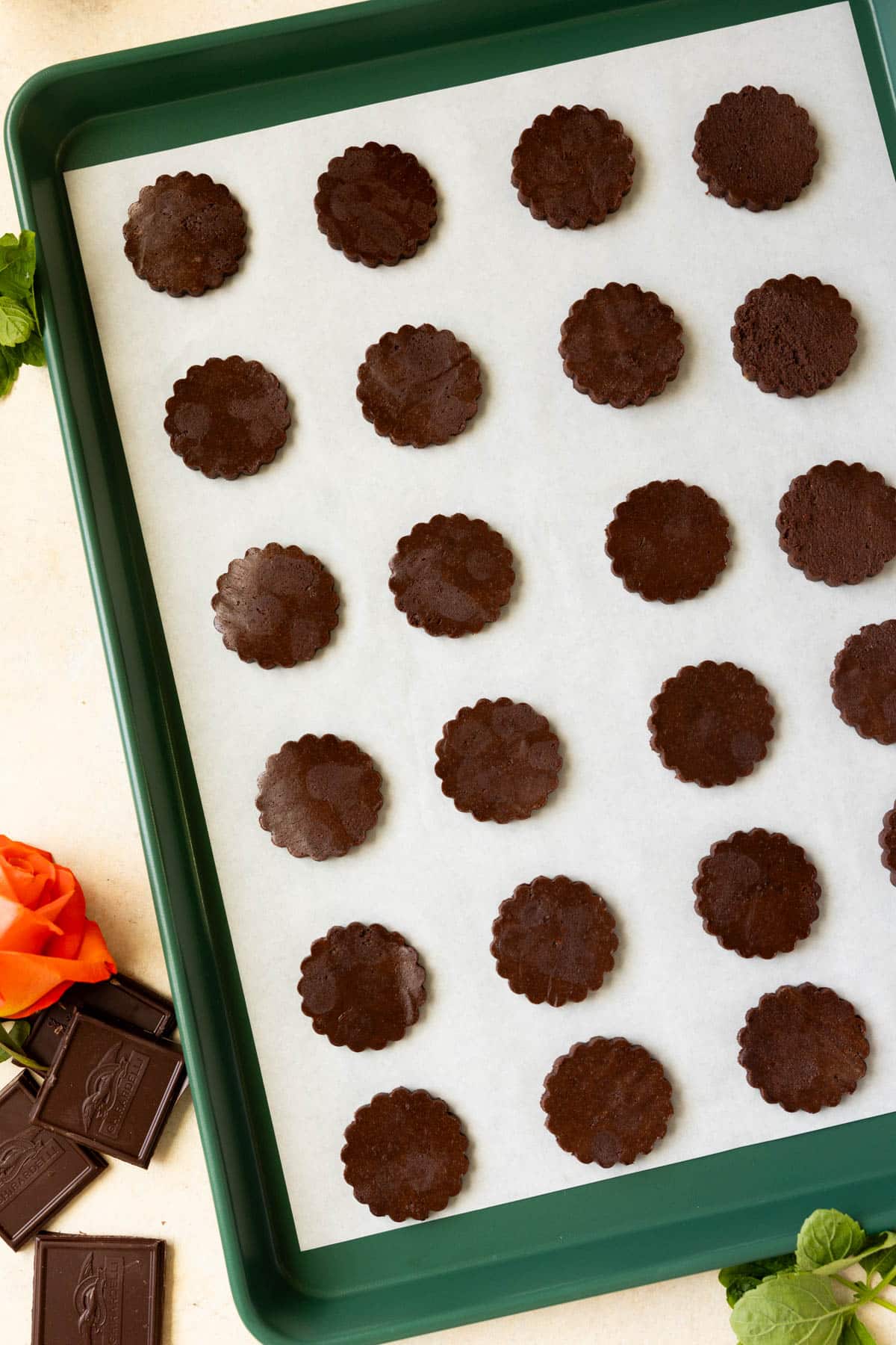 thin mint cut out cookies on a green baking sheet lined with parchment paper. 