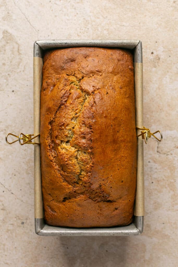 a freshly baked loaf of zucchini banana bread in a loaf pan. 