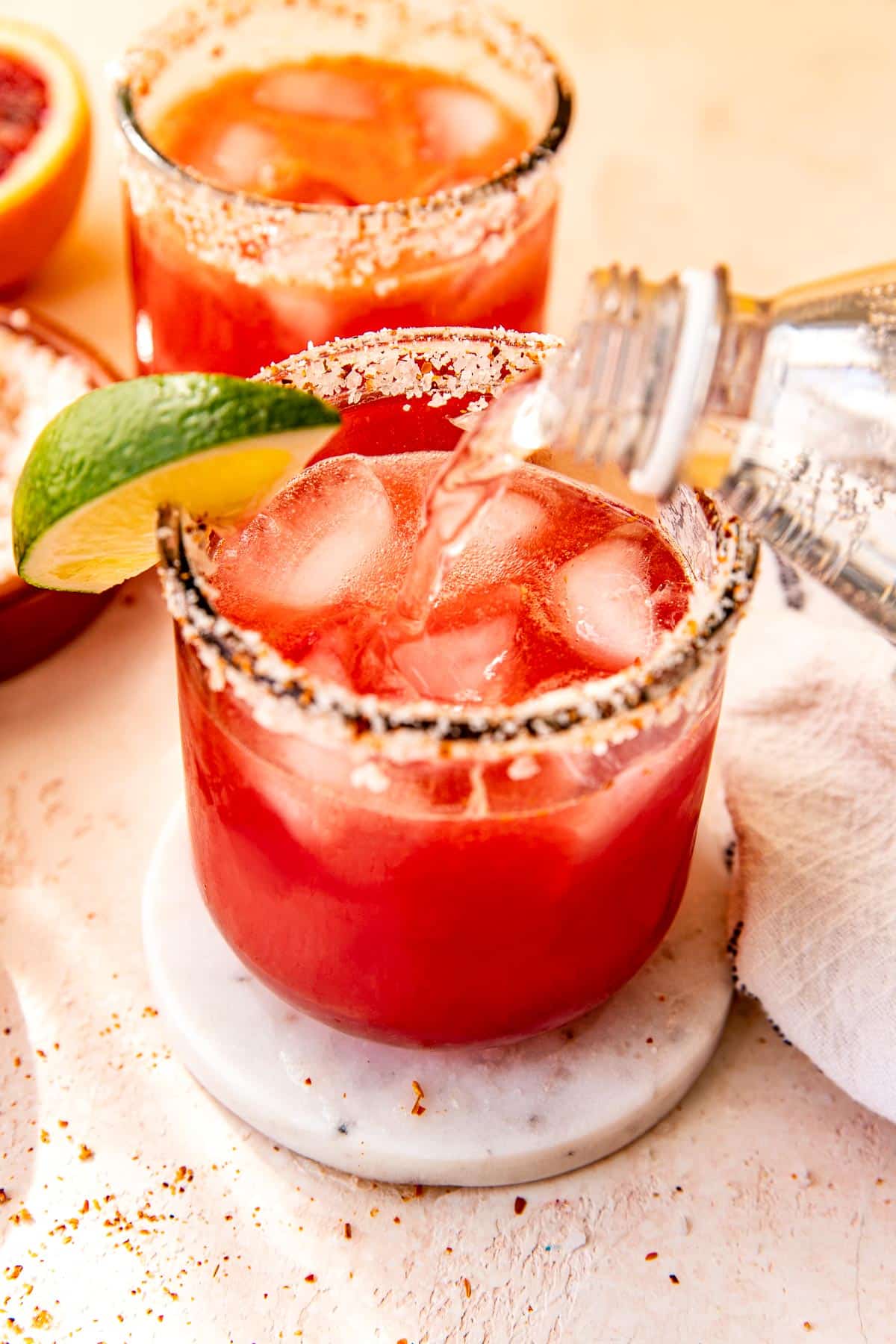 a blood orange margarita with sparkling water being poured on top. 