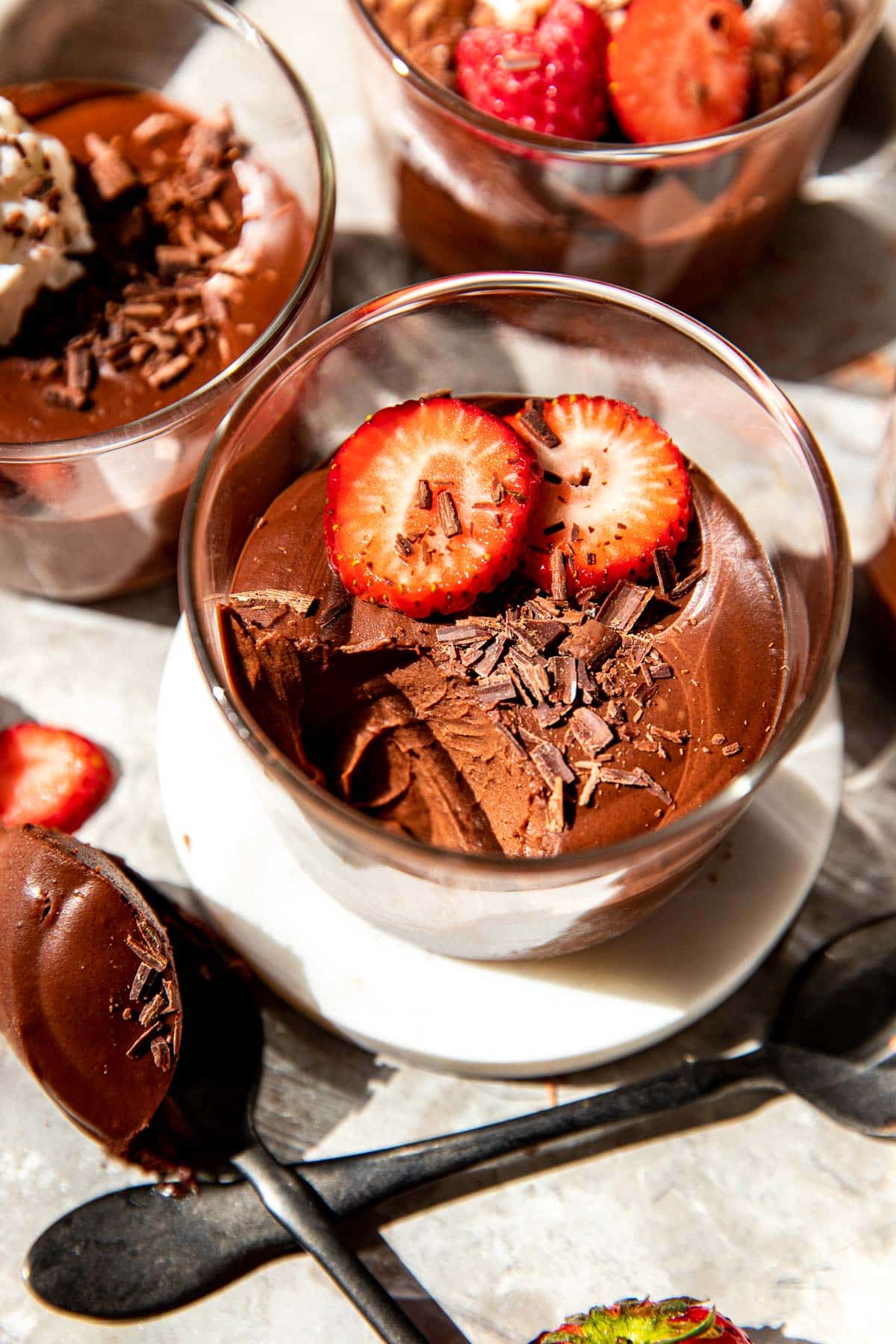 chocolate mousse in glass cups with fruit and chocolate shavings on top. 