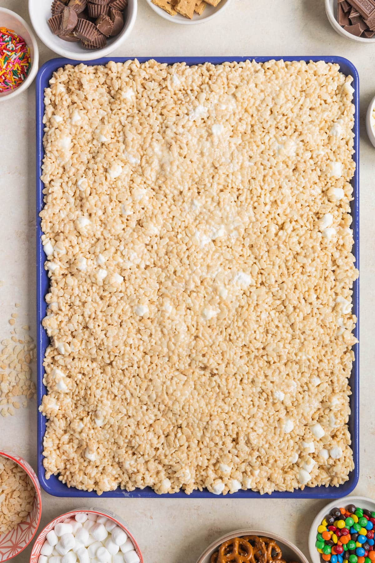 rice krispies spread out on a blue sheeet pan. 