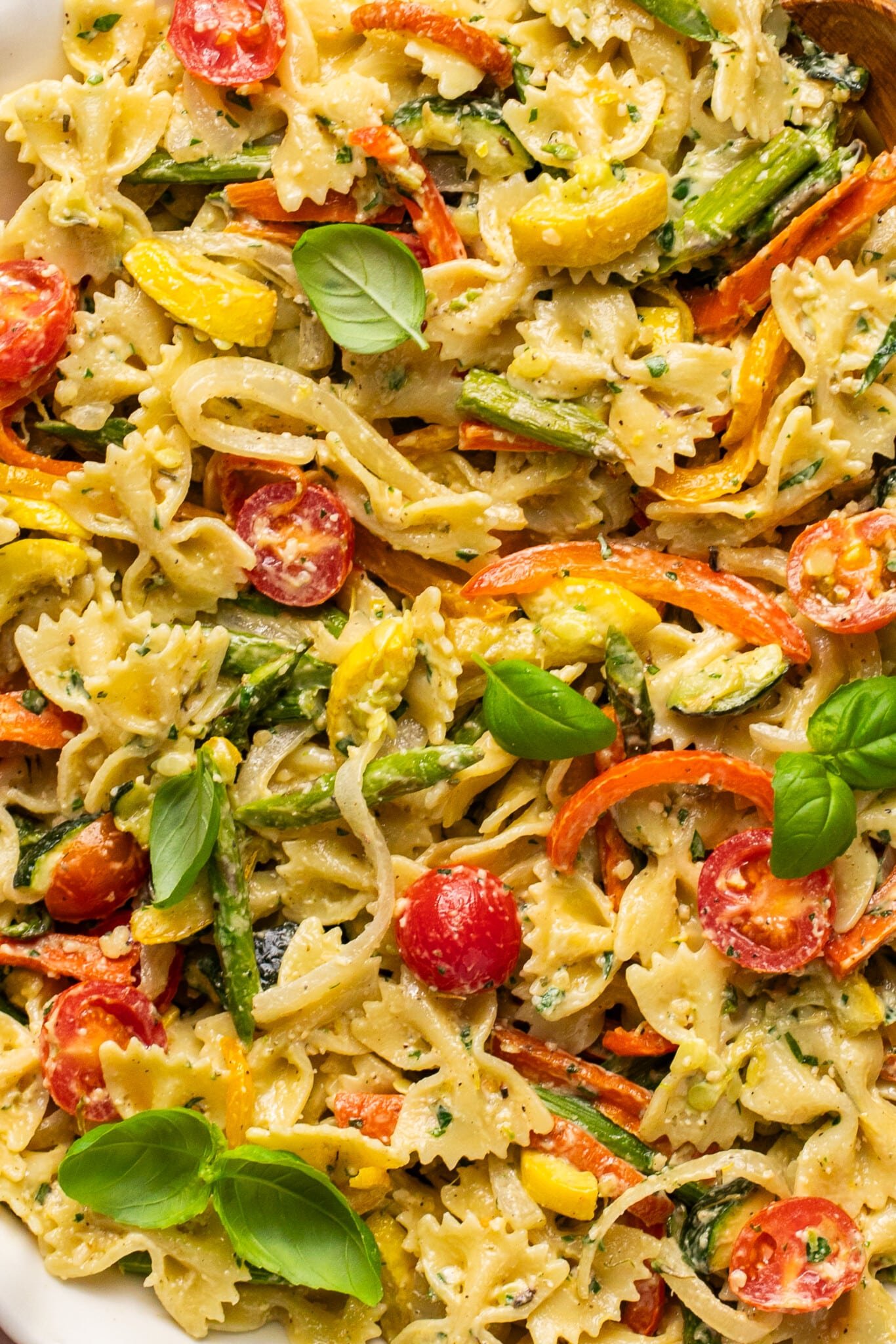 a close up image of bow tie pasta with roasted veggies and fresh basil on top. 